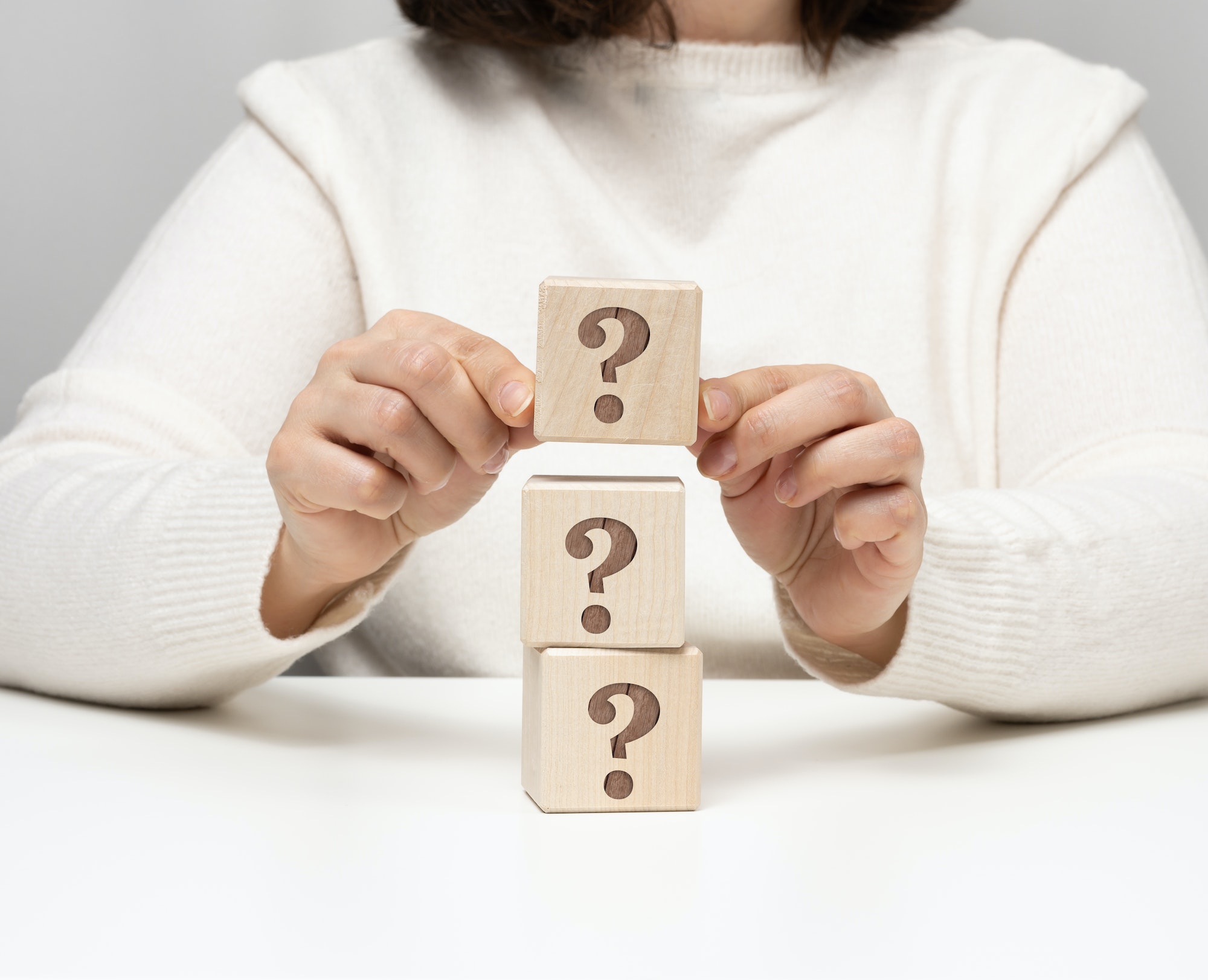 Female hand holding a wooden cube with a question mark